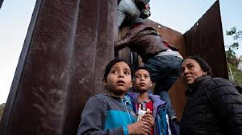 'Markaziy Amerikalik muhojirlar chegaradagi devorga chiqib olishdi'ning rasmi